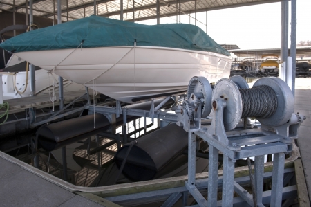 expensive pleasure boat safely stored under canopy on a hyrdolic lift in a dock